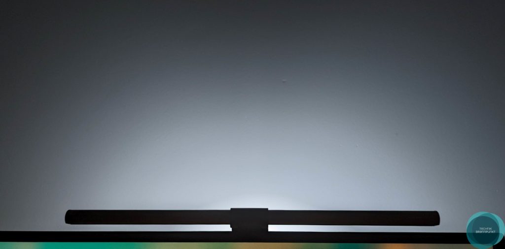 BenQ Screenbar Halo im Test - Hochwertige und platzsparende Schreibtischbeleuchtung BenQ wird vielen als Monitor Hersteller bekannt sein. Die Firma hat in der Vergangenheit bereits aber auch unter anderem sogenannte Screenbars im Portfolio, die bei vielen Arbeitsplätzen an Beliebtheit gewonnen haben. Im Gegensatz zu einer normalen Schreibtischlampe, lässt sich die Screenbar platzsparend auf dem Monitor positionieren und leuchtet ohne Reflexionen am Bildschirm fokussiert die Arbeitsfläche aus. Die neue BenQ Screenbar Halo bringt neben einer kabellosen Steuerung auch eine Hintergrundbeleuchtung mit sich.